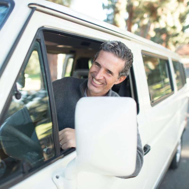 a happy man driving a white vehicle